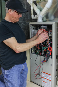 HVAC repair in Spring Lake being done by repairman. Technician is shown in front of open panel with wires out.