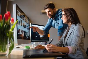 Lacey web design professional shown with her client reviewing pictures on a large monitor